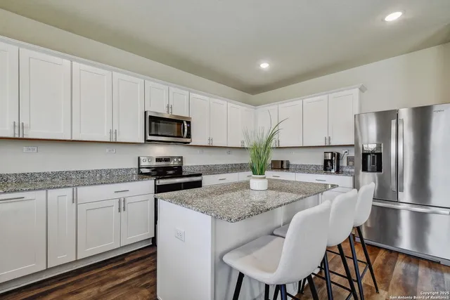 a kitchen with granite countertop white cabinets and stainless steel appliances