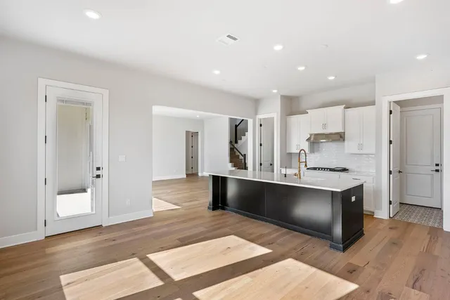 a large kitchen with stainless steel appliances a large counter top a sink and a refrigerator