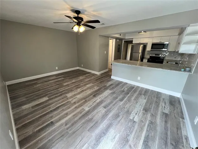 a view of kitchen and empty room with wooden floor