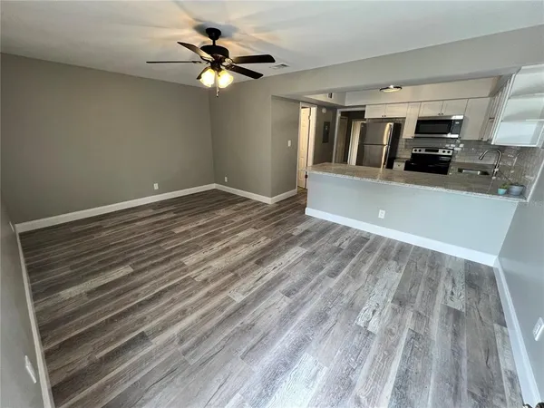 a view of kitchen and empty room with wooden floor
