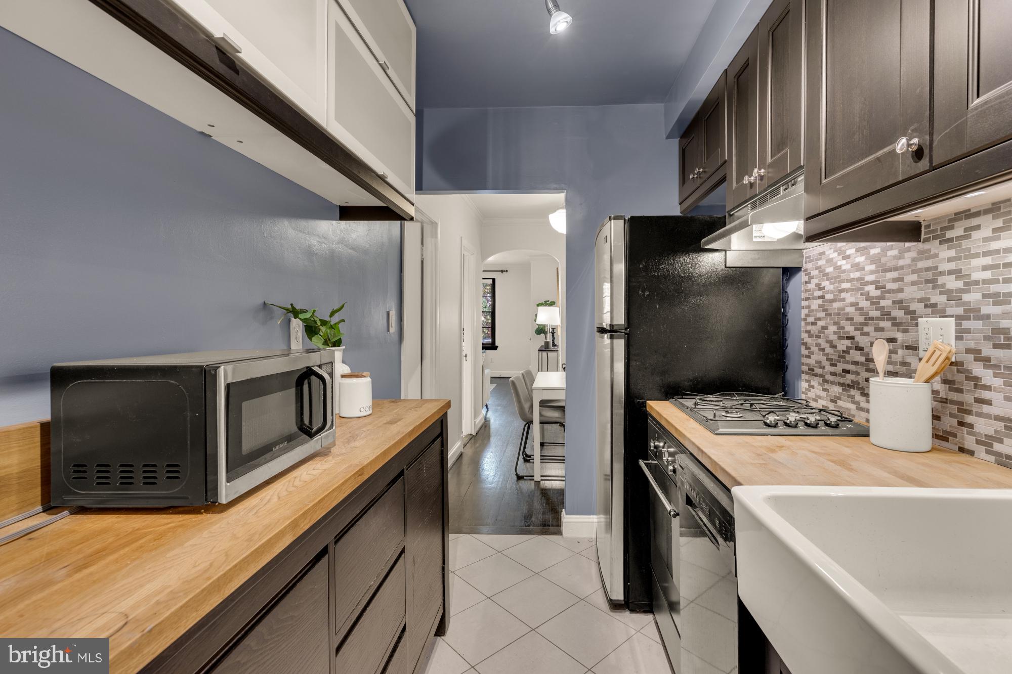 1127 C Street Southeast, Unit 2 Washington, DC 20003 - Photo 13 of 17 a kitchen with stainless steel appliances kitchen island granite countertop a refrigerator a stove and a sink with wooden floor