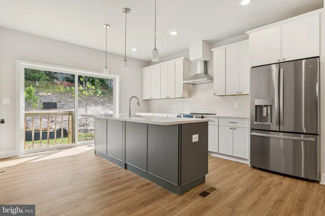 a kitchen with kitchen island granite countertop wooden floors white cabinets and stainless steel appliances