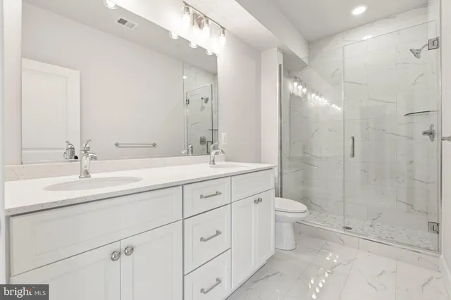 a bathroom with double sink a toilet a shower and a mirror