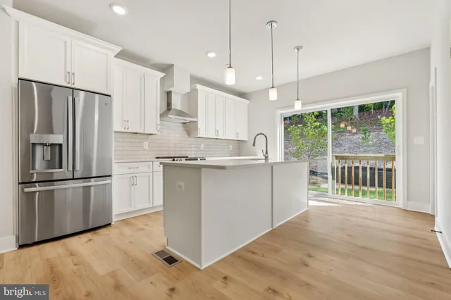 a kitchen with stainless steel appliances granite countertop a refrigerator a stove a sink and a wooden floors