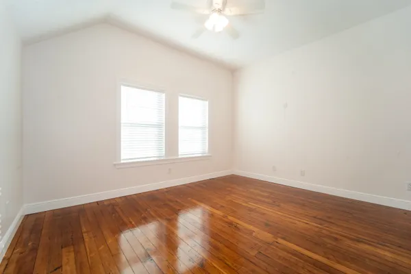an empty room with wooden floor and windows