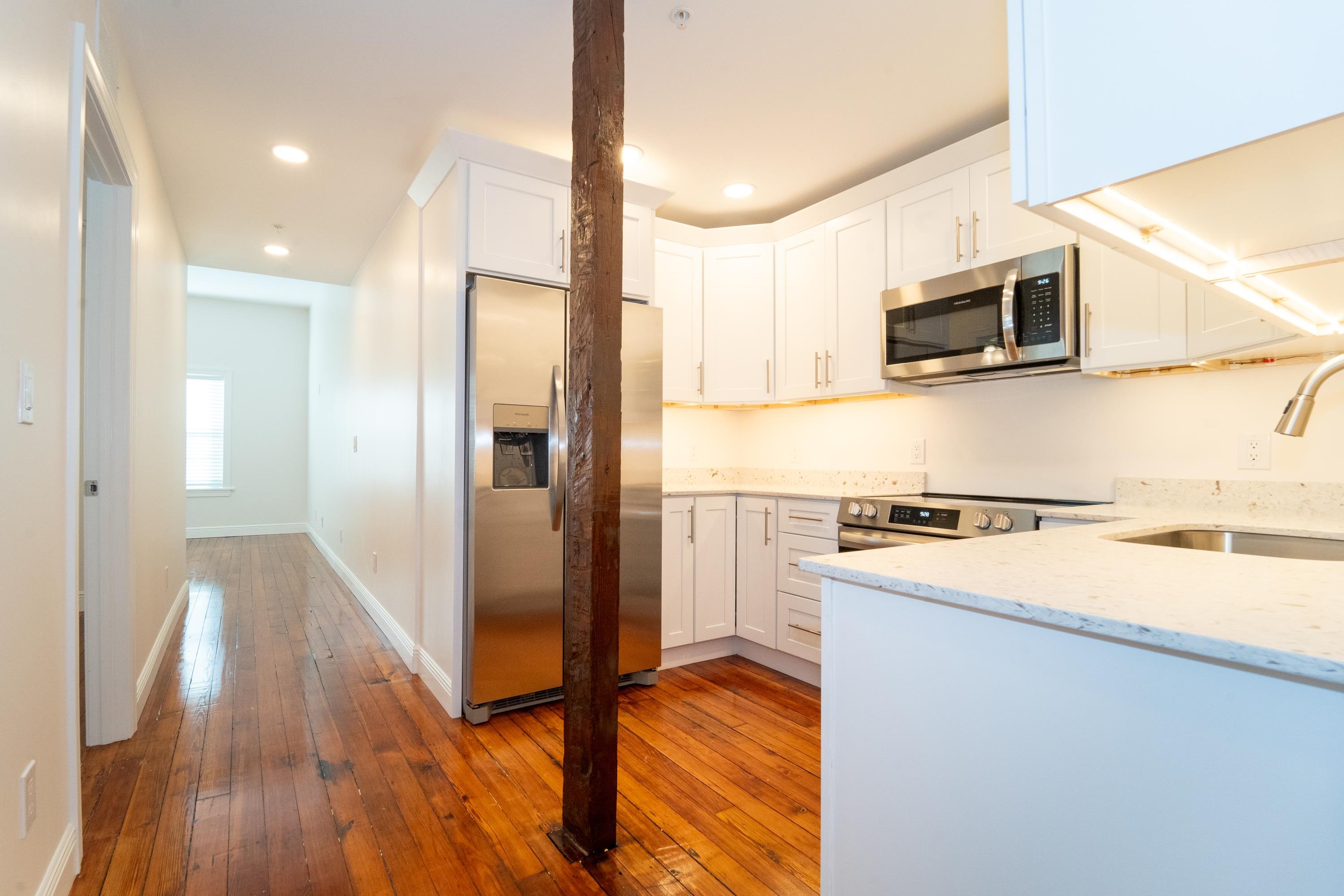 11 Aviles Street, Unit 2D St. Augustine, FL 32084 - Photo 6 of 24 a kitchen with stainless steel appliances granite countertop a refrigerator a stove and a microwave with wooden floor