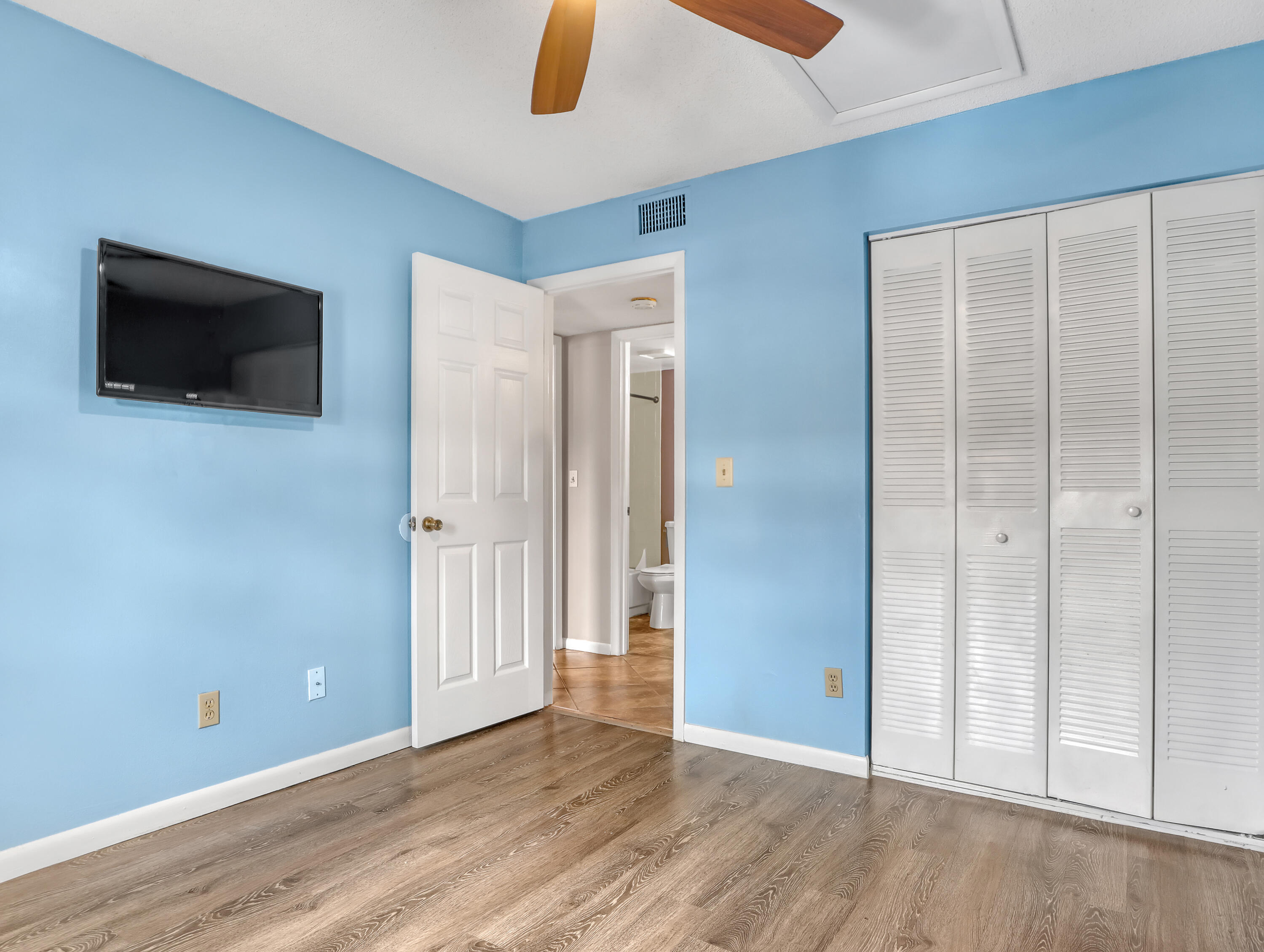 592 North Wickham Road, Unit 18 Melbourne, FL 32935 - Photo 21 of 29 a view of an empty room with wooden floor and a ceiling fan
