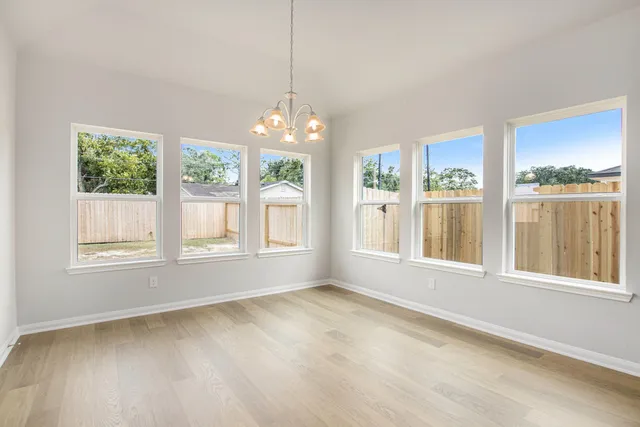 a view of an empty room with a window and wooden floor