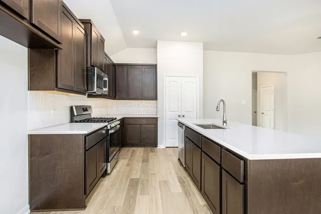 a kitchen with a sink stove top oven and cabinets