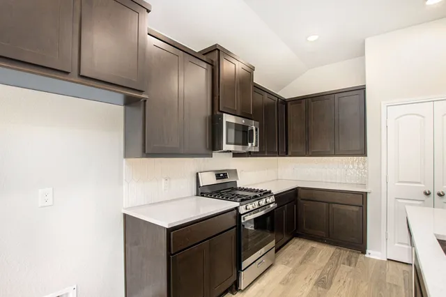 a kitchen with stainless steel appliances a sink a stove a microwave a refrigerator a sink and cabinets