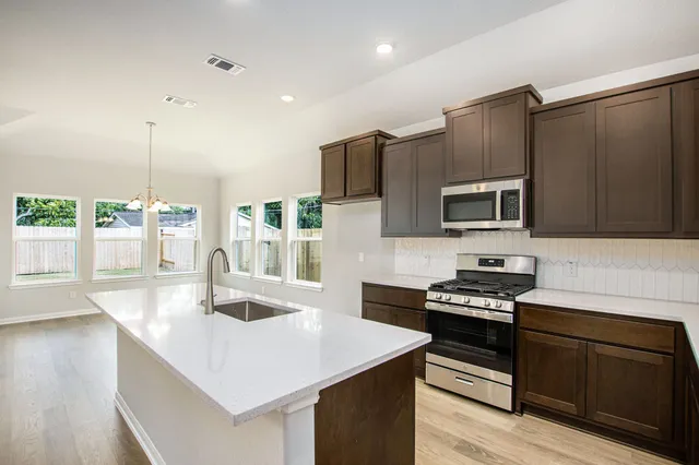 a kitchen with stainless steel appliances a stove a sink a microwave a refrigerator and cabinets