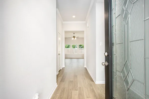 a view of a hallway with wooden floor and a bathroom
