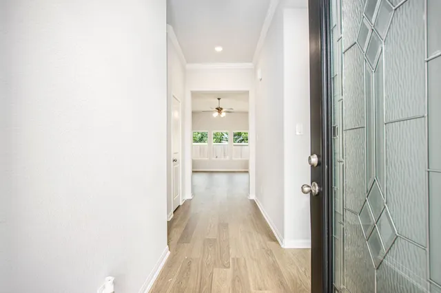 a view of a hallway with wooden floor and a bathroom