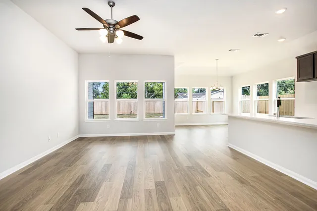 a view of an empty room with a window and wooden floor