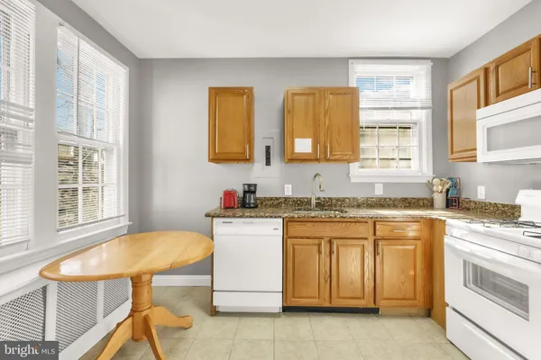 a kitchen with a stove a sink and white cabinets