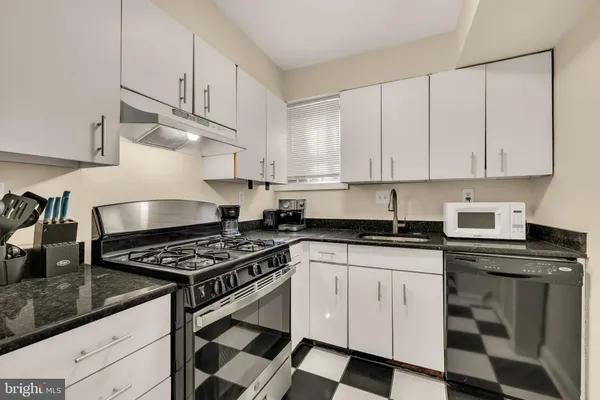a kitchen with granite countertop white cabinets and appliances