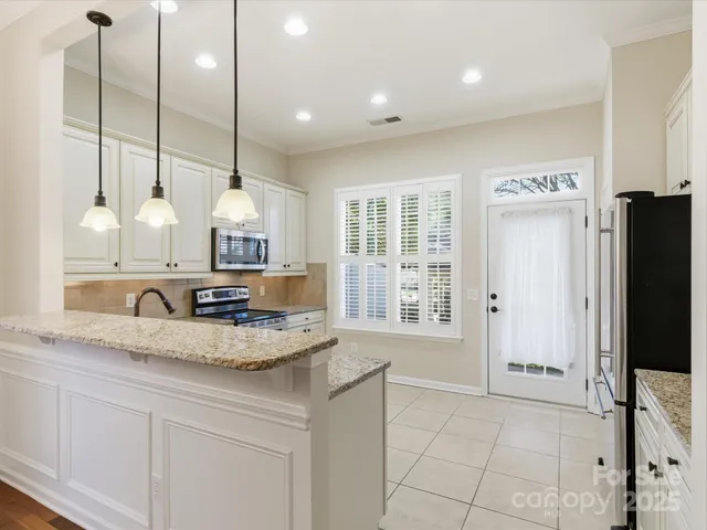 a kitchen with stainless steel appliances granite countertop a sink a oven a refrigerator and a counter top space
