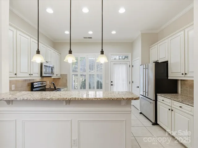 a kitchen with stainless steel appliances kitchen island granite countertop a refrigerator a oven and a sink with cabinets