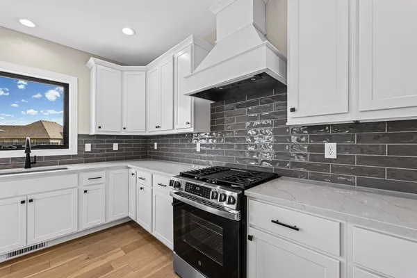 a kitchen with granite countertop white cabinets stainless steel appliances and a sink