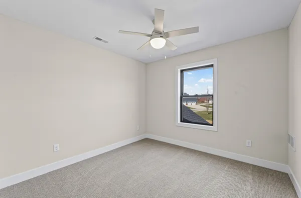 an empty room with a window and a fan