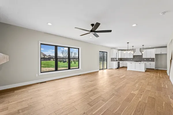 a view of an empty room with a window and kitchen view