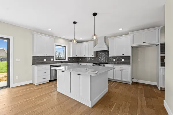 a kitchen with white cabinets stainless steel appliances and wooden floor