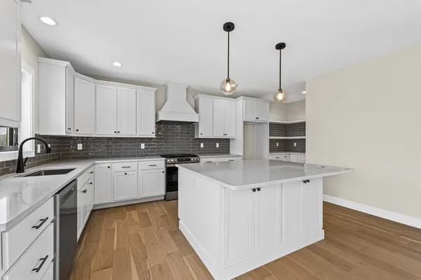 a kitchen with stainless steel appliances granite countertop a sink stove and white cabinets with wooden floor