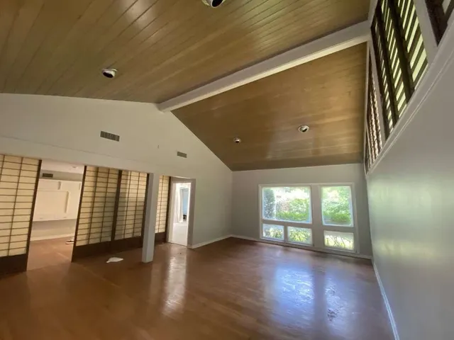 a view of an empty room with wooden floor and a window