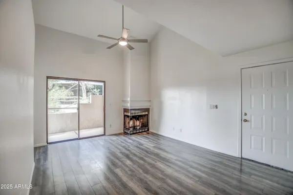 an empty room with wooden floor a ceiling fan and windows
