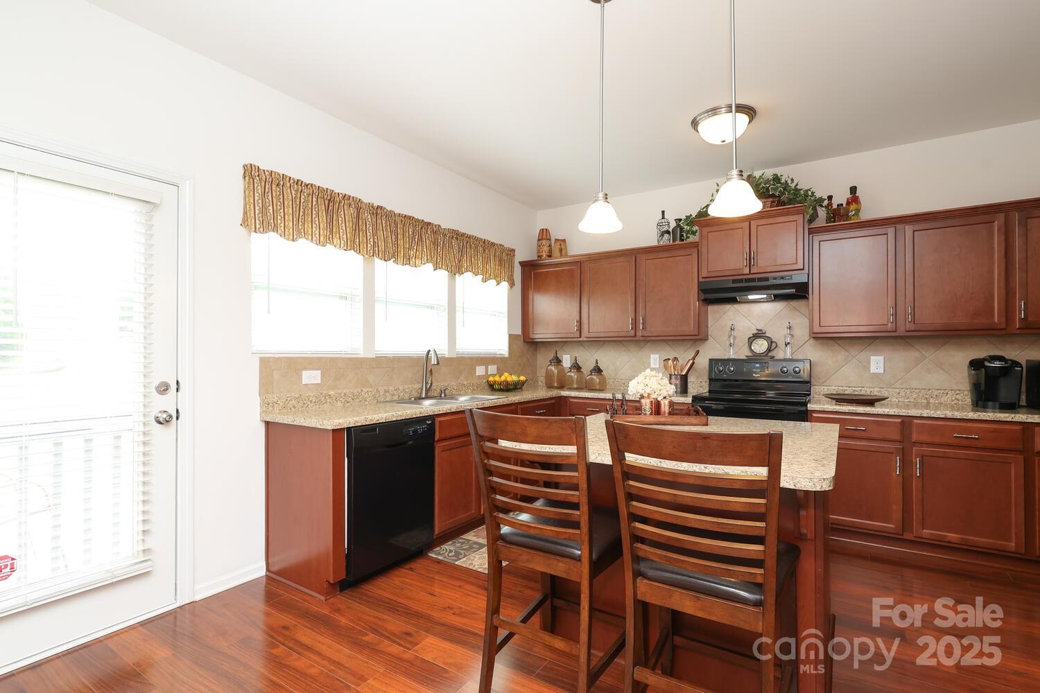2104 Gillette Drive Clover, SC 29710 - Photo 13 of 33 a kitchen with stainless steel appliances granite countertop a stove top oven a sink a dining table and chairs with wooden floor