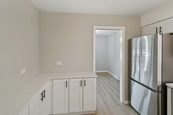a kitchen with a refrigerator and wooden floor