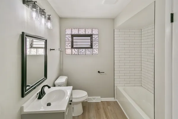 a bathroom with a toilet a sink a mirror and bathtub