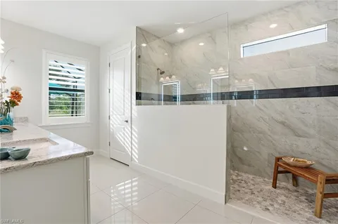 a bathroom with a granite countertop sink a large mirror a and a window