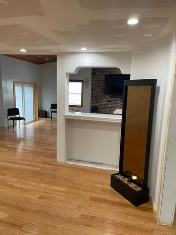 a living room with stainless steel appliances furniture a flat screen tv and kitchen view