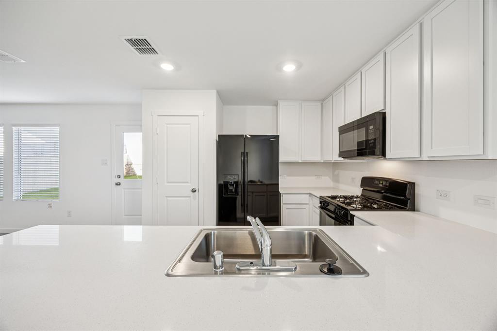 11550 Gammon Avenue Rhome, TX 76078 - Photo 10 of 29 a kitchen with a sink a counter top space cabinets and stainless steel appliances
