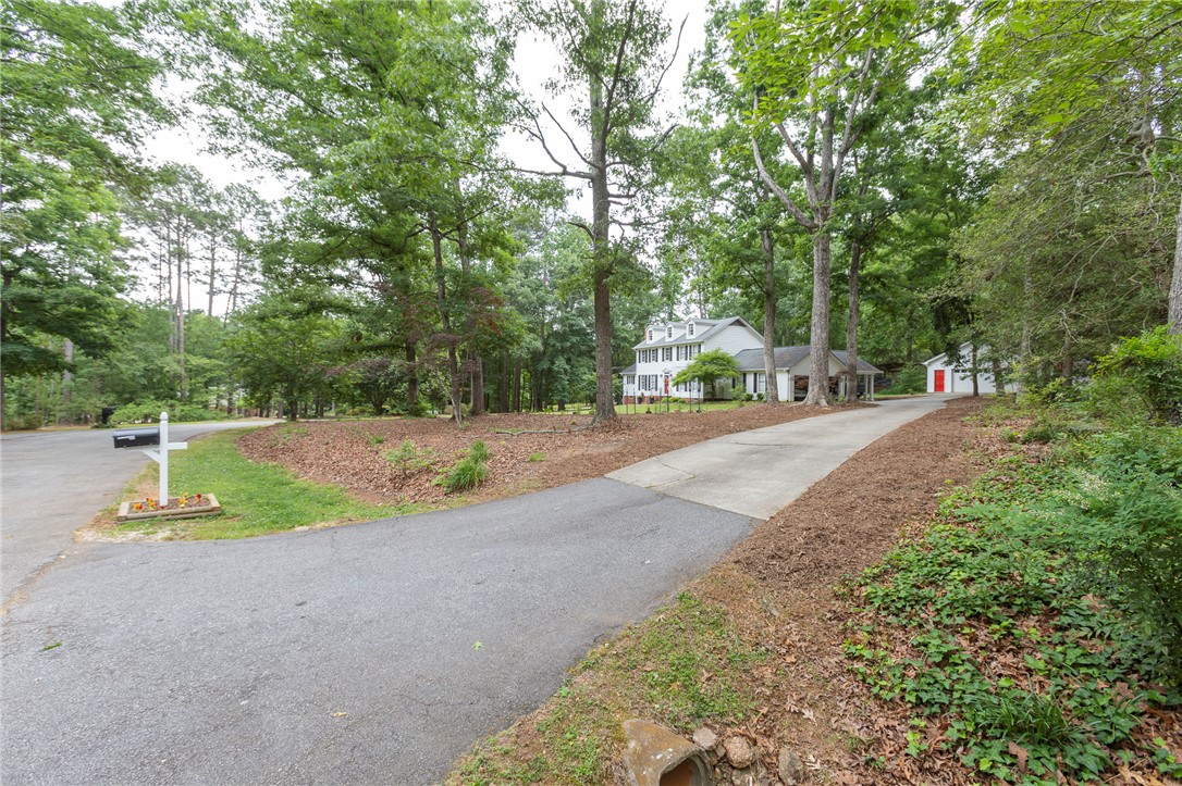 203 Oak Hollow Pendleton, SC 29670 - Photo 49 of 50 A private driveway leads to a secluded white residence, nestled amidst mature, verdant trees.