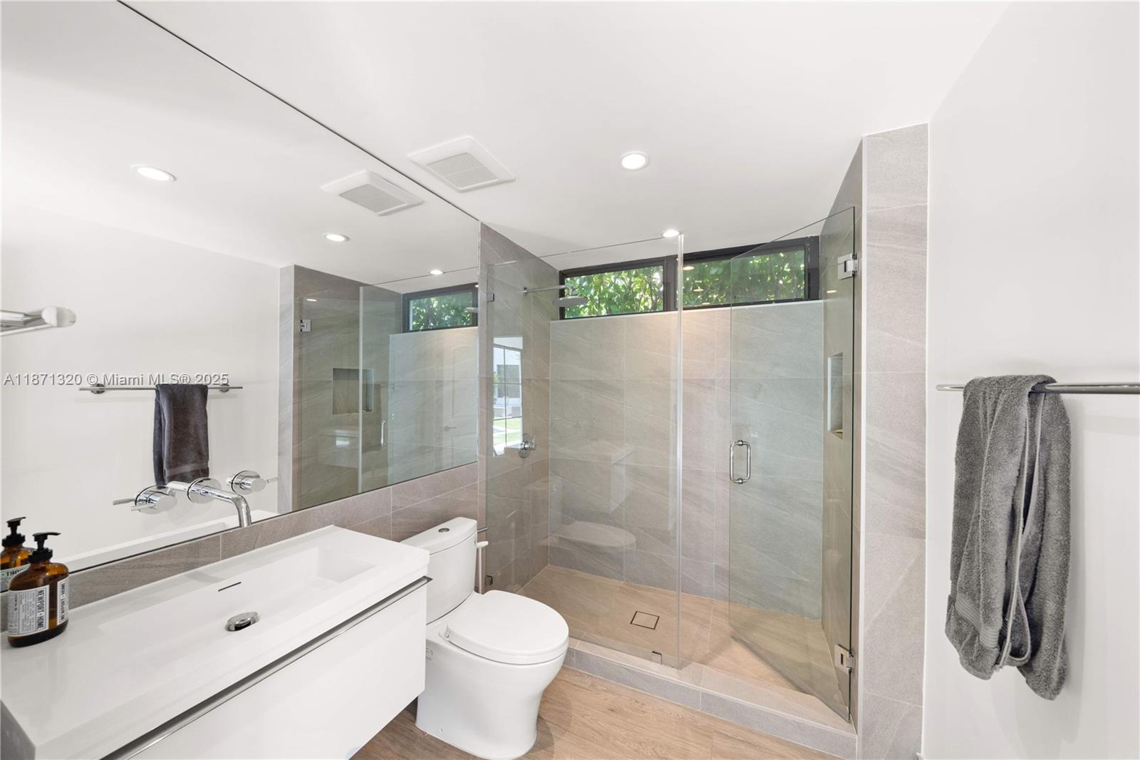 5728 Pine Tree Drive Miami Beach, FL 33140 - Photo 38 of 49 a bathroom with a shower sink vanity mirror and toilet