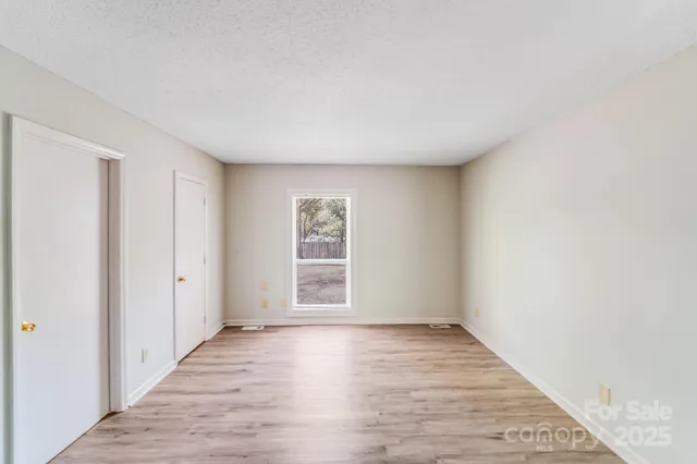 an empty room with wooden floor & windows