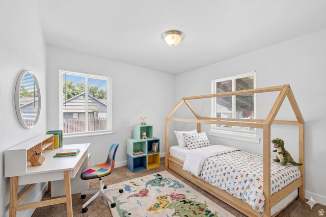 7879 Oak Street Midvale, UT 84047 - Photo 11 of 32 Bright room featuring two windows with blinds, a built-in flush-mount ceiling light fixture, and neutral-toned wall-to-wall carpeting