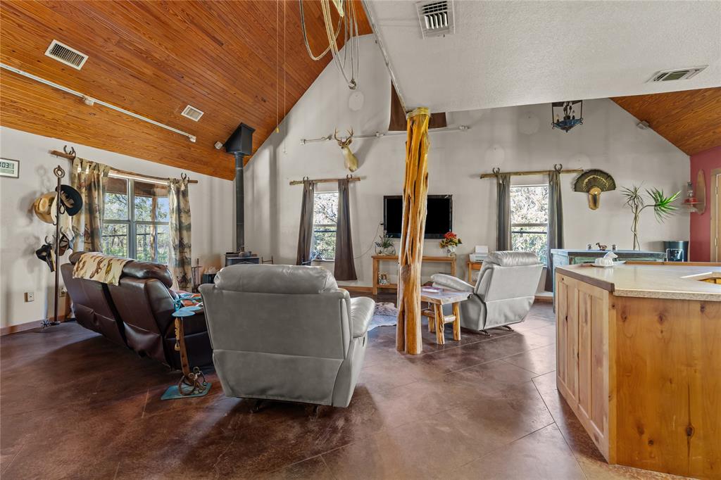 262 North Cheyenne Springtown, TX 76082 - Photo 8 of 35 Living room with a wood stove, high vaulted ceiling, concrete floors, plenty of natural light, and wood ceiling