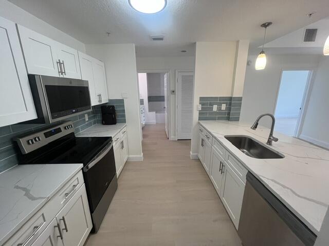 1155 Main Street, Unit 209 Jupiter, FL 33458 - Photo 5 of 10 a kitchen with a sink a stove and a refrigerator