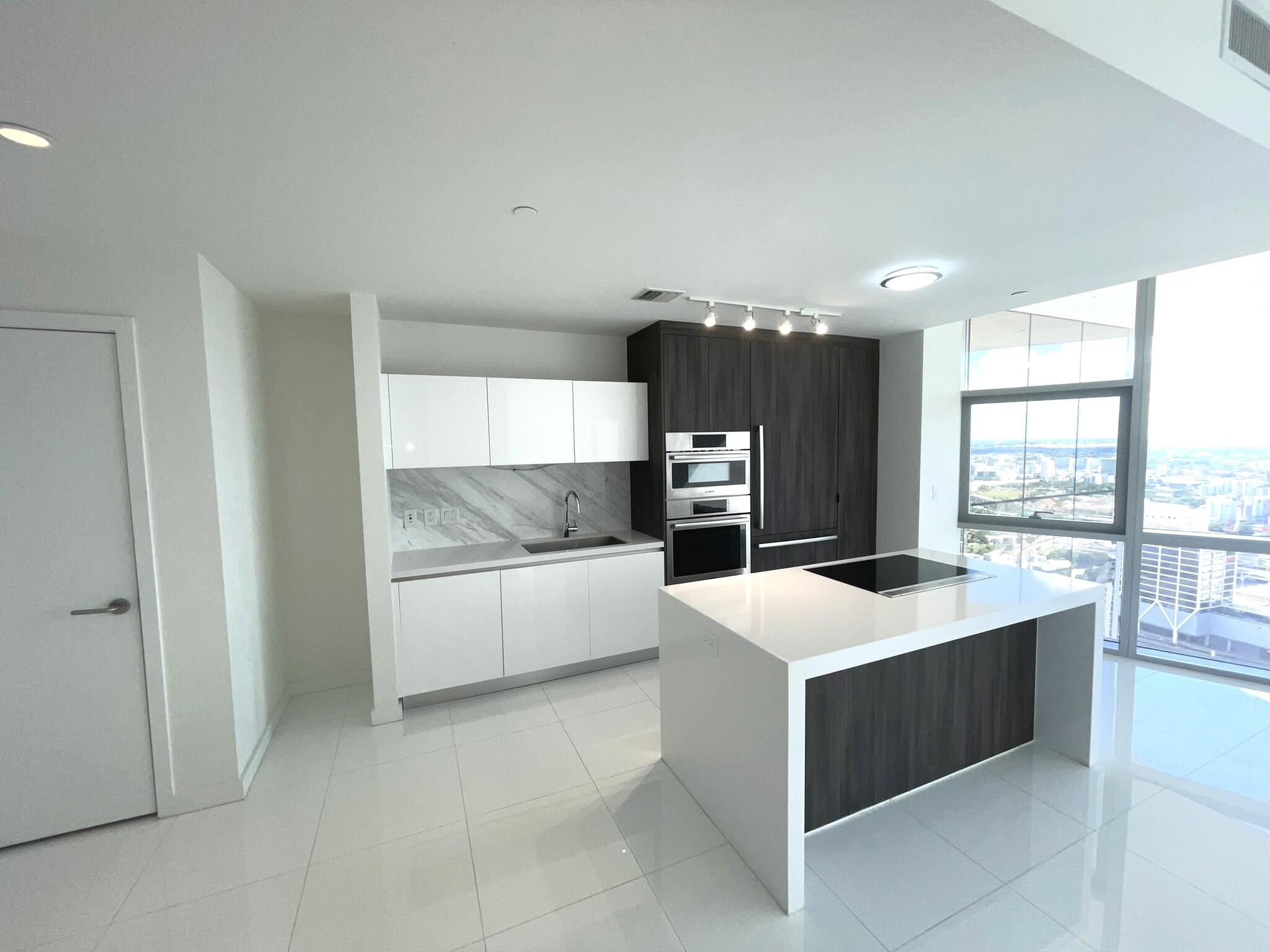 a large white kitchen with a stove top oven a sink a counter space and windows