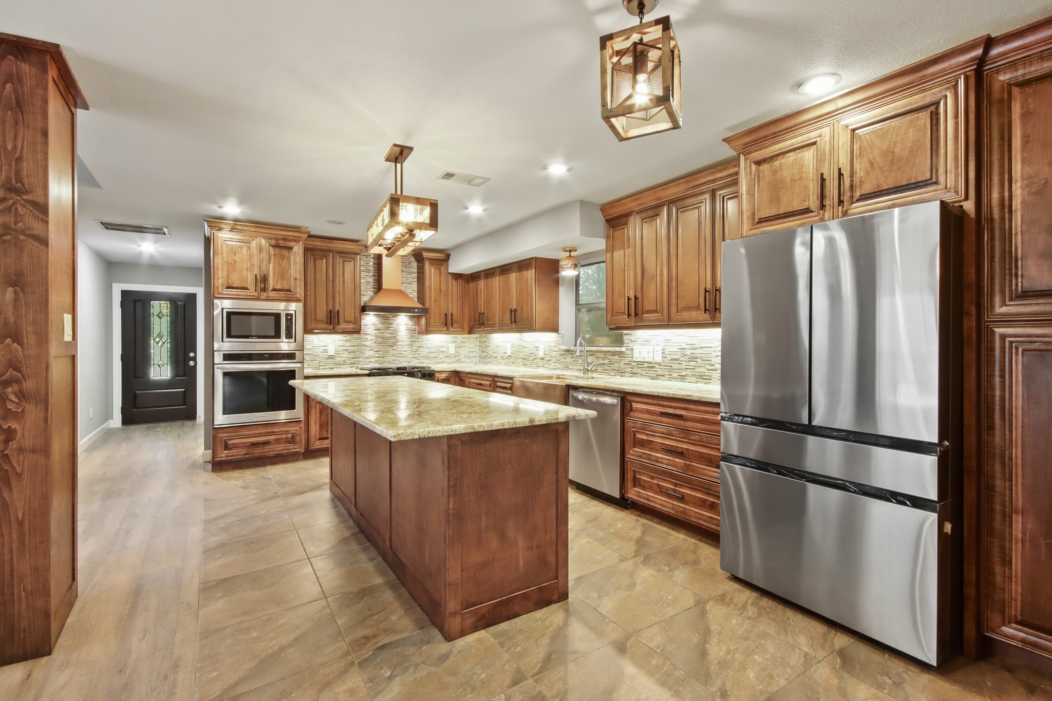 35 Susan Drive Cleveland, TX 77327 - Photo 7 of 33 This kitchen features rich wood cabinetry, a large island with granite countertops, stainless steel appliances, and stylish pendant lighting. The open layout and modern finishes create a warm and inviting space.