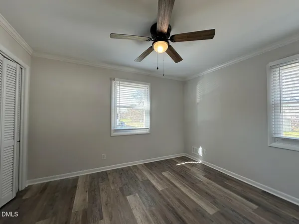 a view of empty room with wooden floor and fan