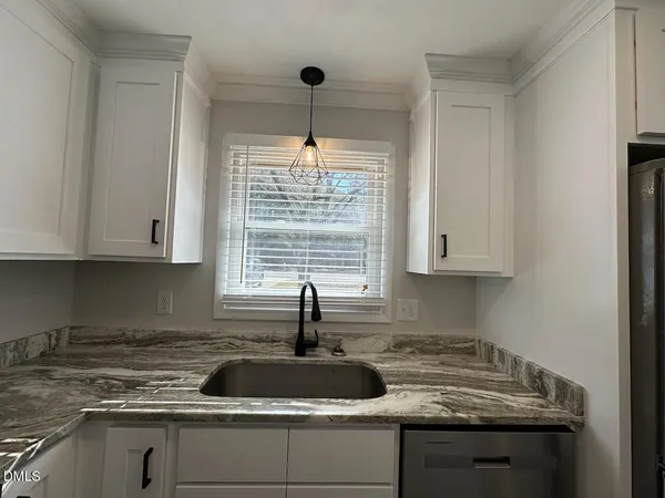 a kitchen with granite countertop a sink and white cabinets