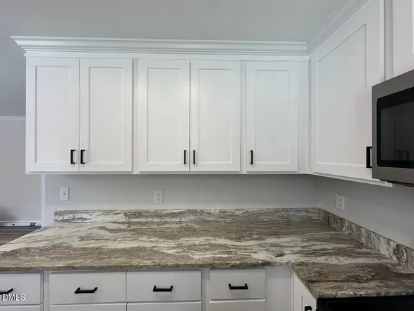 a view of kitchen with granite countertop white cabinets