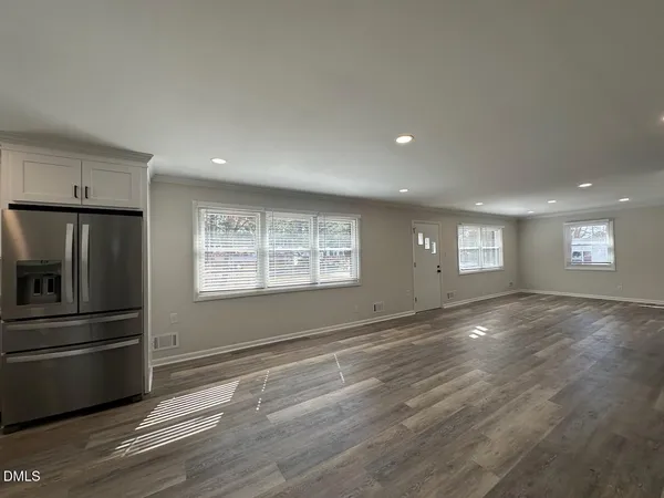a view of an empty room with a window and wooden floor