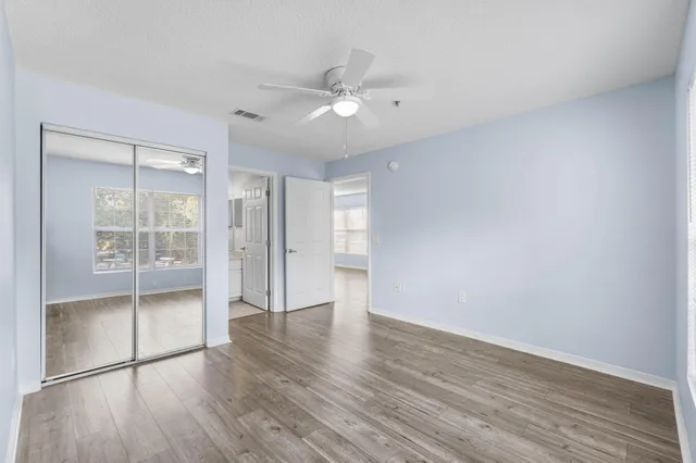 an empty room with wooden floor and a ceiling fan