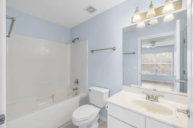 a bathroom with a bathtub shower sink vanity mirror and toilet