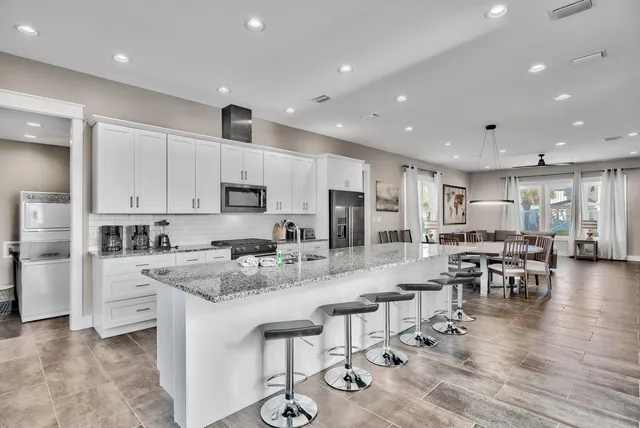 a large kitchen with kitchen island a dining table chairs and white cabinets